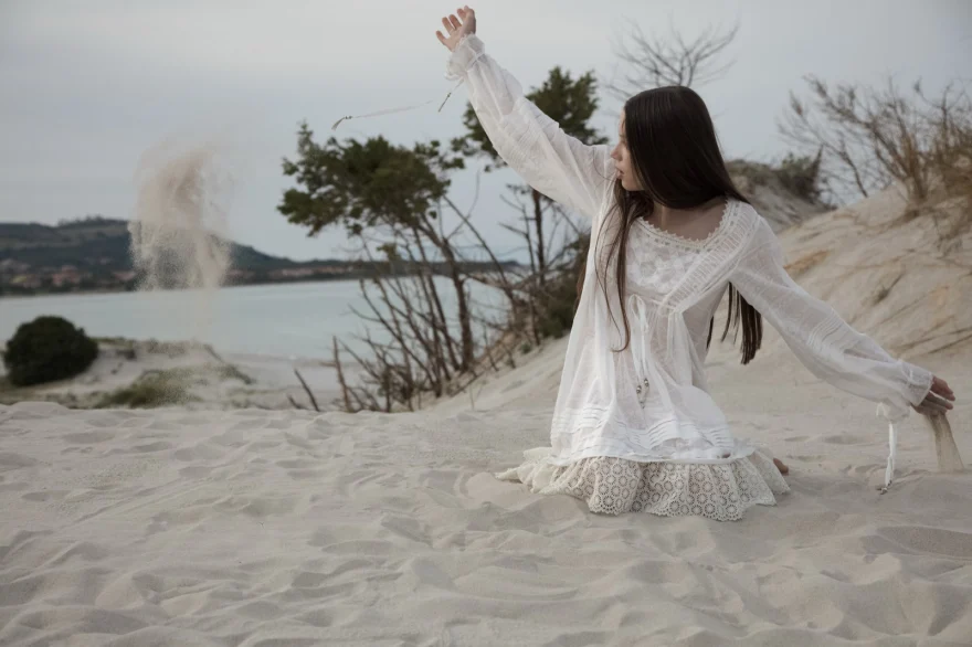 Model kneeling on the dunes as sand is thrown into the air, ETRO × SHOT Magazine editorial photographed by Ina Cenusa