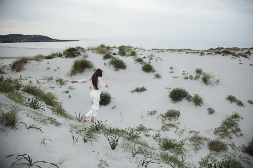 Model in white walking across pale dunes and scrub, ETRO × SHOT Magazine editorial photographed by Ina Cenusa
