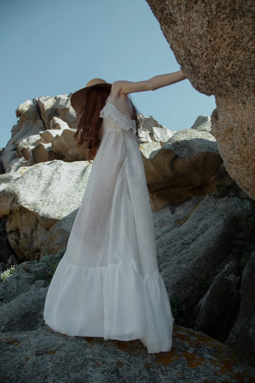 Model in a long white dress leaning against granite rocks, SHOT Magazine editorial photographed by Ina Cenusa