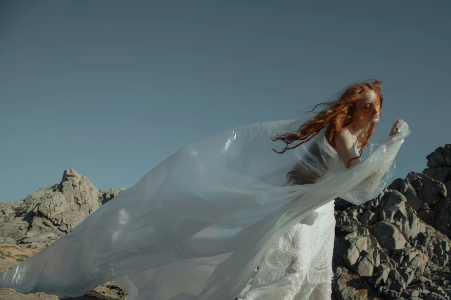 White fabric caught by the wind across the rocks under a clear sky, SHOT Magazine editorial photographed by Ina Cenusa