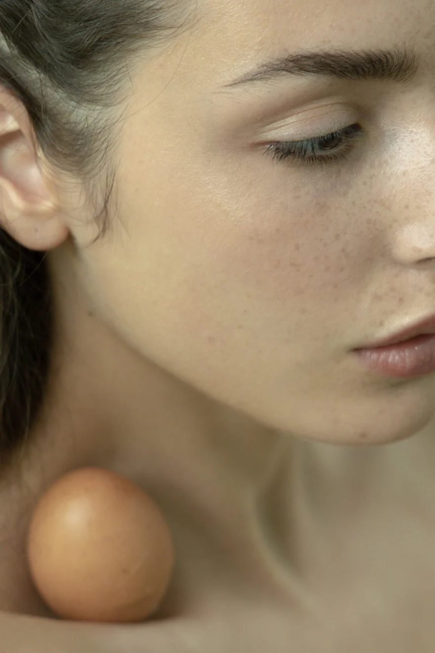 Close-up of an egg balanced on a bare shoulder, SHOT Magazine editorial photographed by Ina Cenusa