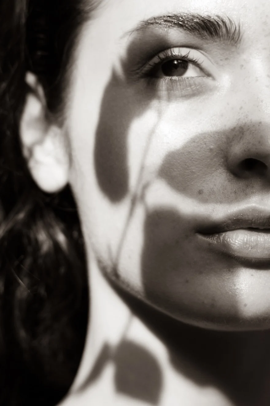 Black and white close-up with grass shadows falling across the face, SHOT Magazine editorial photographed by Ina Cenusa