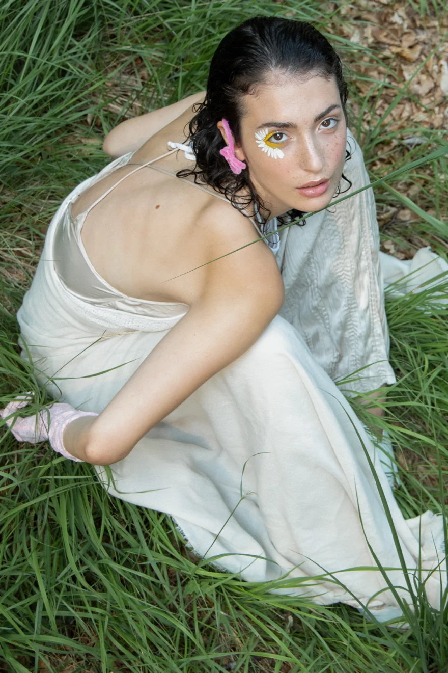Overhead view of the model seated in tall grass in a pale dress, SHOT Magazine editorial photographed by Ina Cenusa