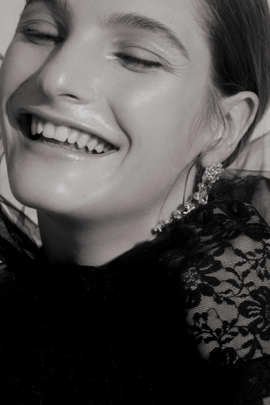 Black and white portrait of a model laughing in black lace and crystal earrings, Iso Model Management editorial photographed by Ina Cenusa