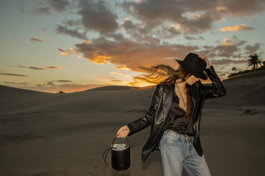 Model with a black bucket bag on the dunes at sunset, closing image of the campaign, Aurora Venezia campaign photographed by Ina Cenusa