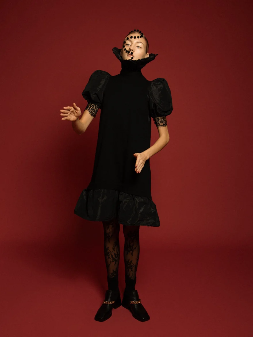 Model in a black puff-sleeve dress against a deep red backdrop, LYX Magazine editorial photographed by Ina Cenusa