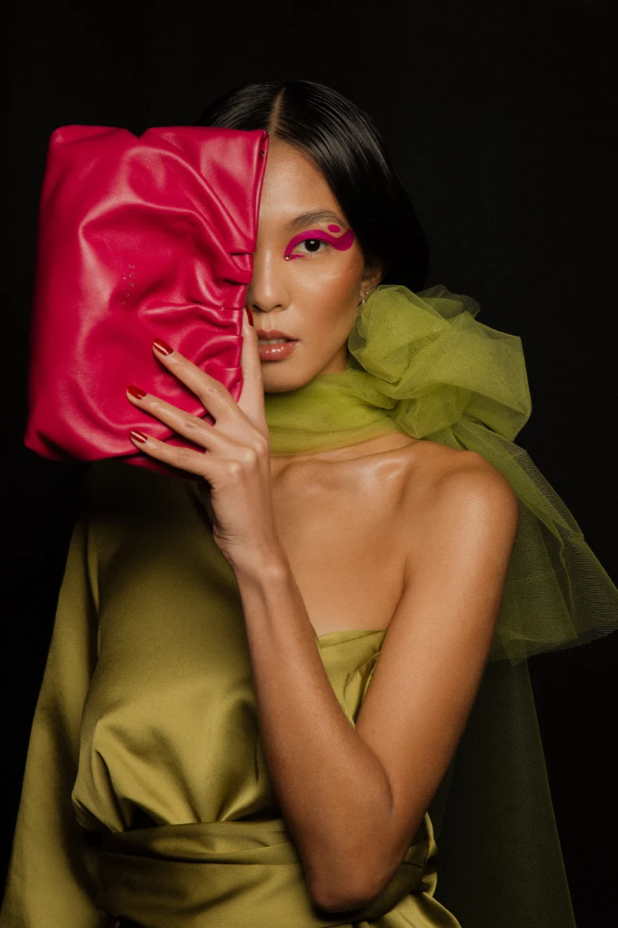 Model in olive green with lime tulle holding a fuchsia bag over her face, LYX Magazine editorial photographed by Ina Cenusa