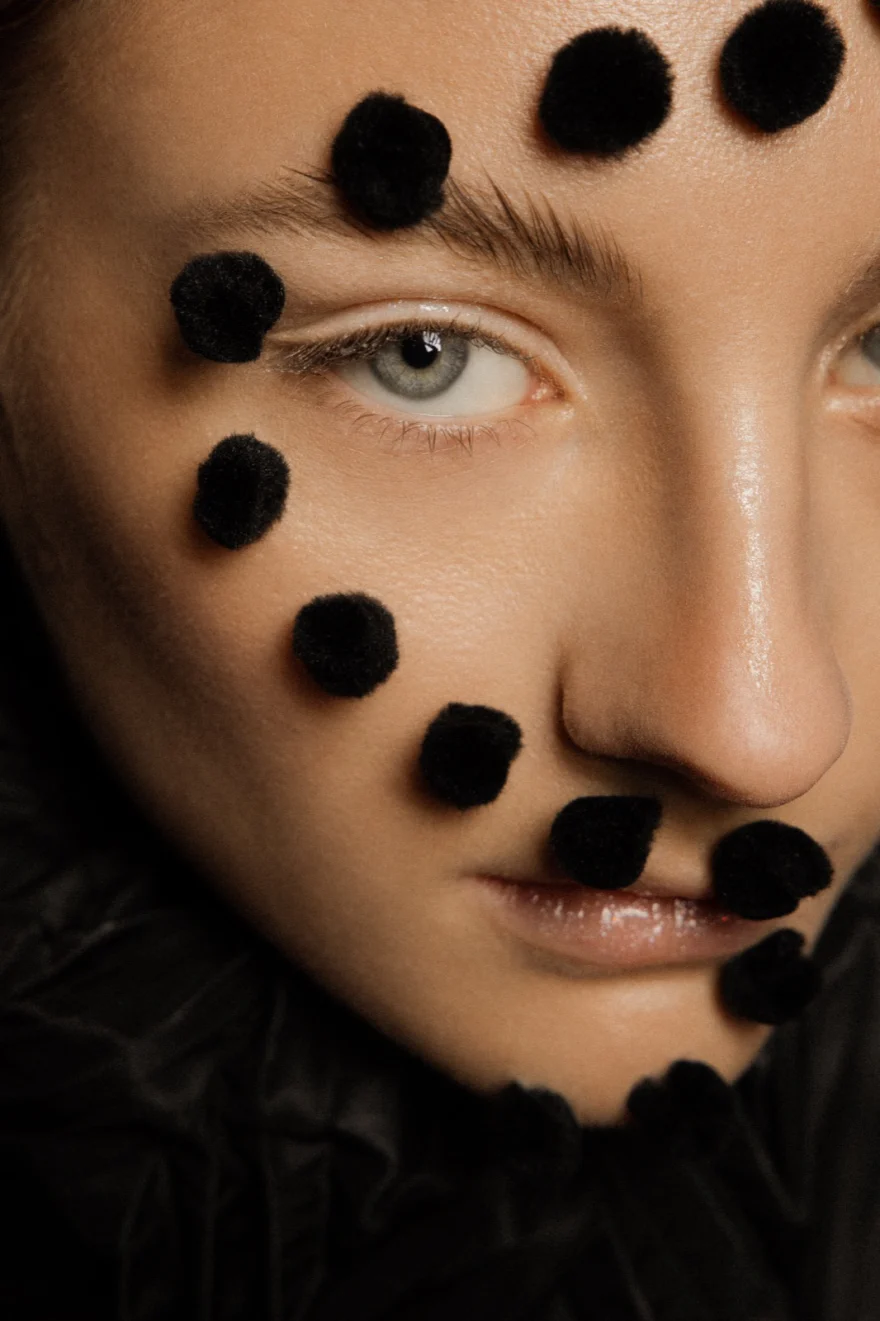Close-up of black pom-poms arranged across the face, LYX Magazine editorial photographed by Ina Cenusa