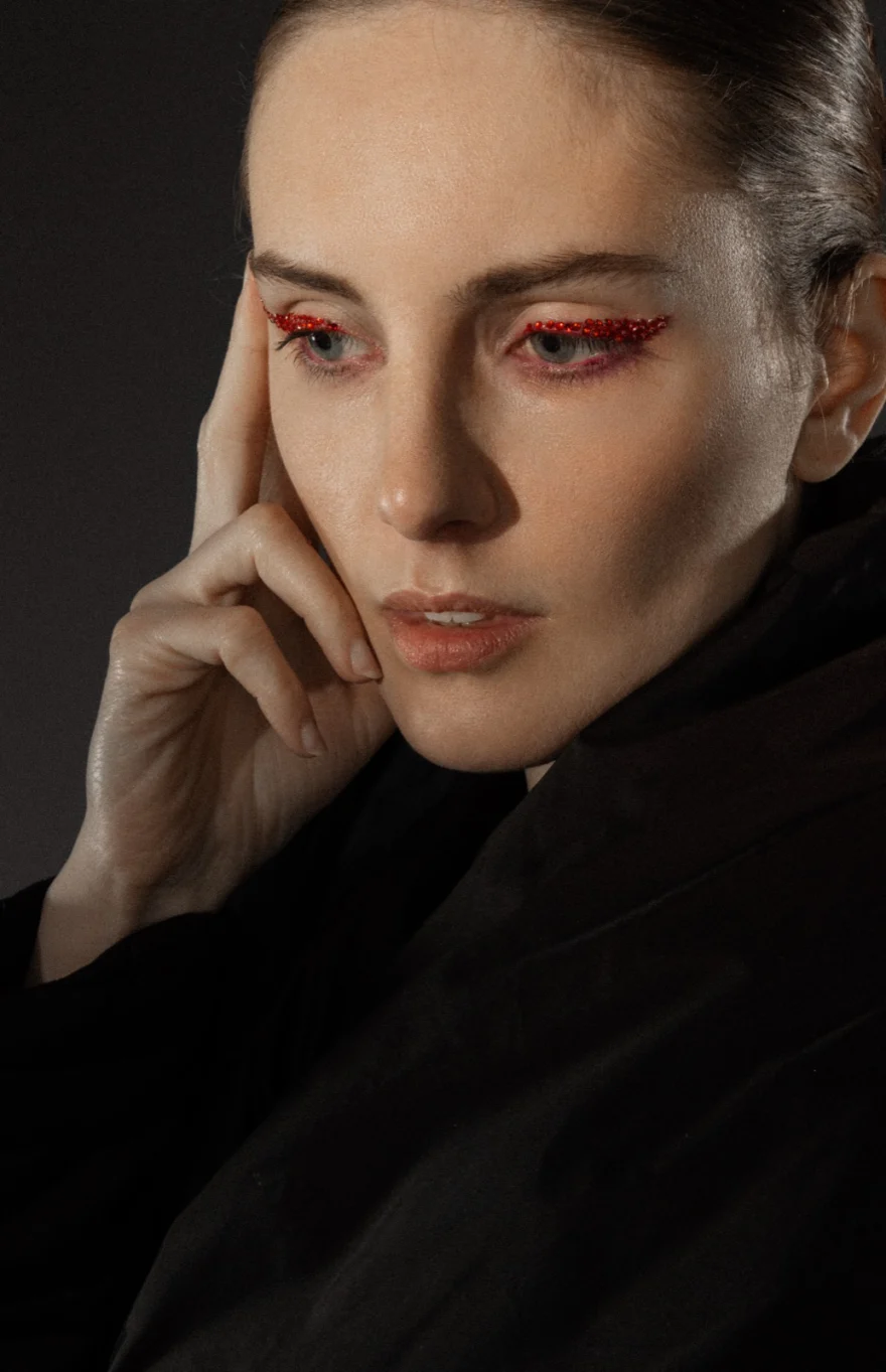 Close portrait with graphic red eyeliner against a dark background, Hunter Magazine editorial photographed by Ina Cenusa