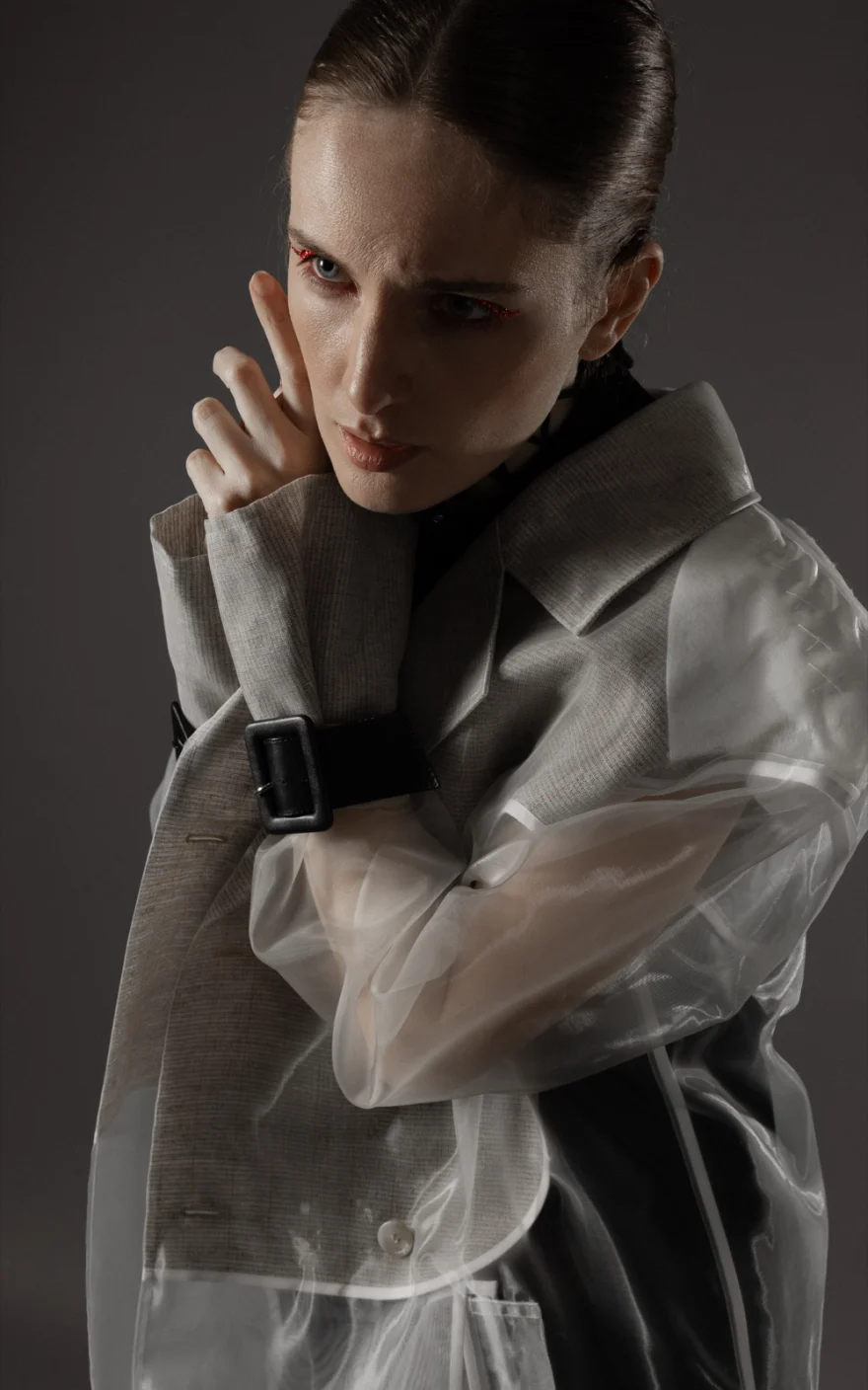 Model standing in a transparent overcoat in a dark studio, Hunter Magazine editorial photographed by Ina Cenusa