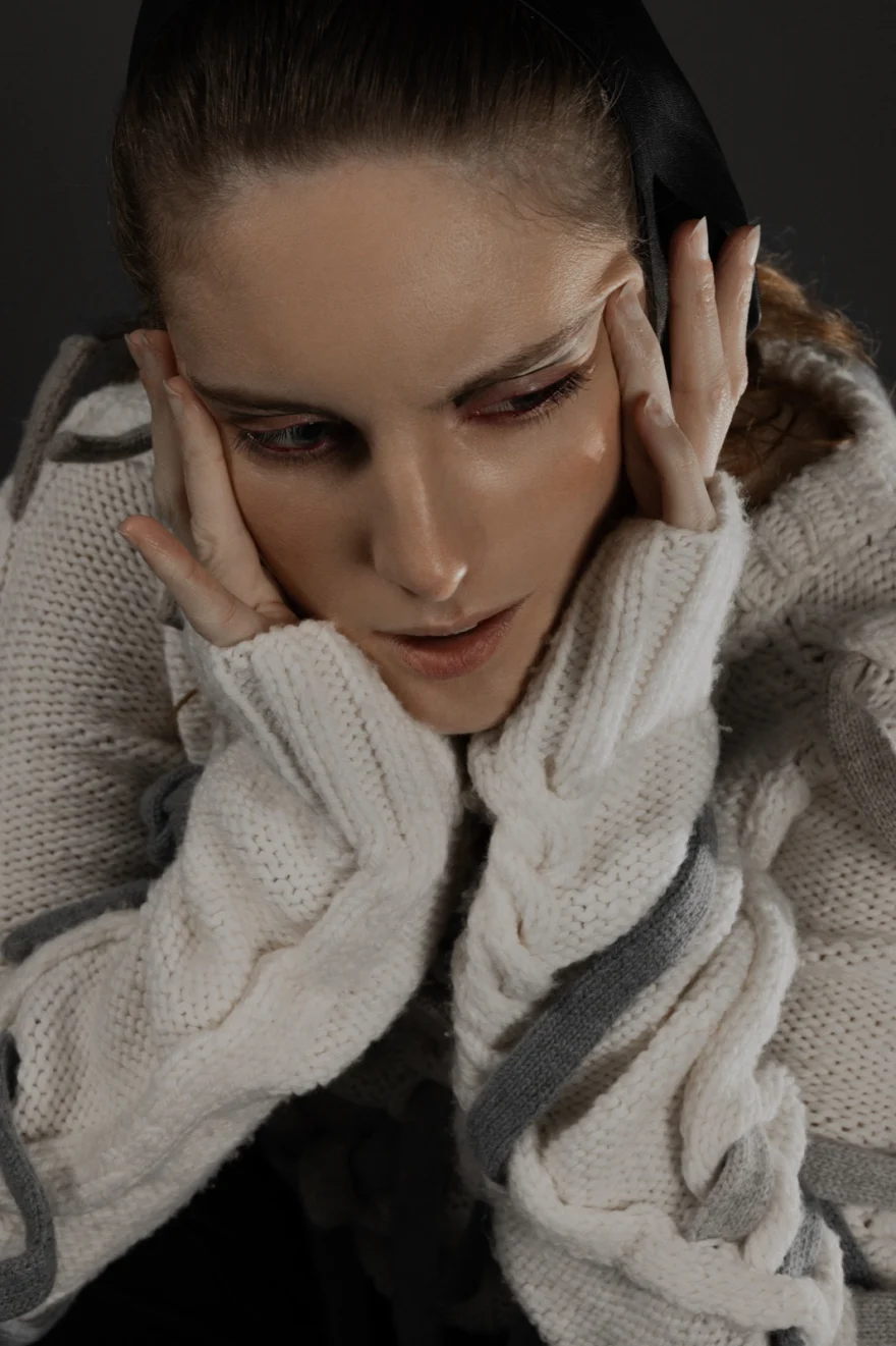 Model in a chunky white knit with both hands framing the face, Hunter Magazine editorial photographed by Ina Cenusa