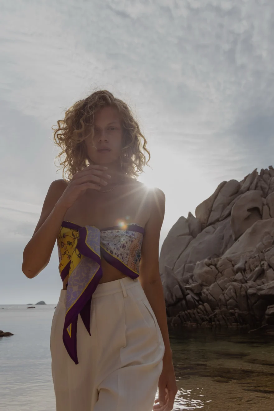 Model in a printed bandeau top backlit by the sun on the Sardinian coast, SHOT Magazine editorial photographed by Ina Cenusa