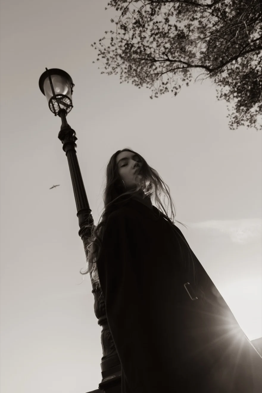 Low-angle shot of the model beside a Venetian lamppost against the sky, Daria personal project photographed by Ina Cenusa