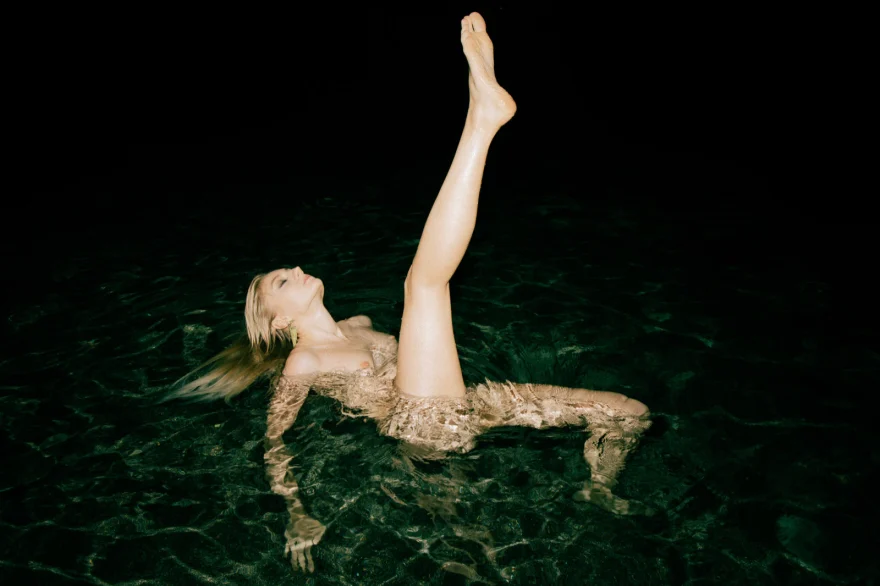 Model floating in dark green water with legs raised, Amalfi Coast personal project photographed by Ina Cenusa