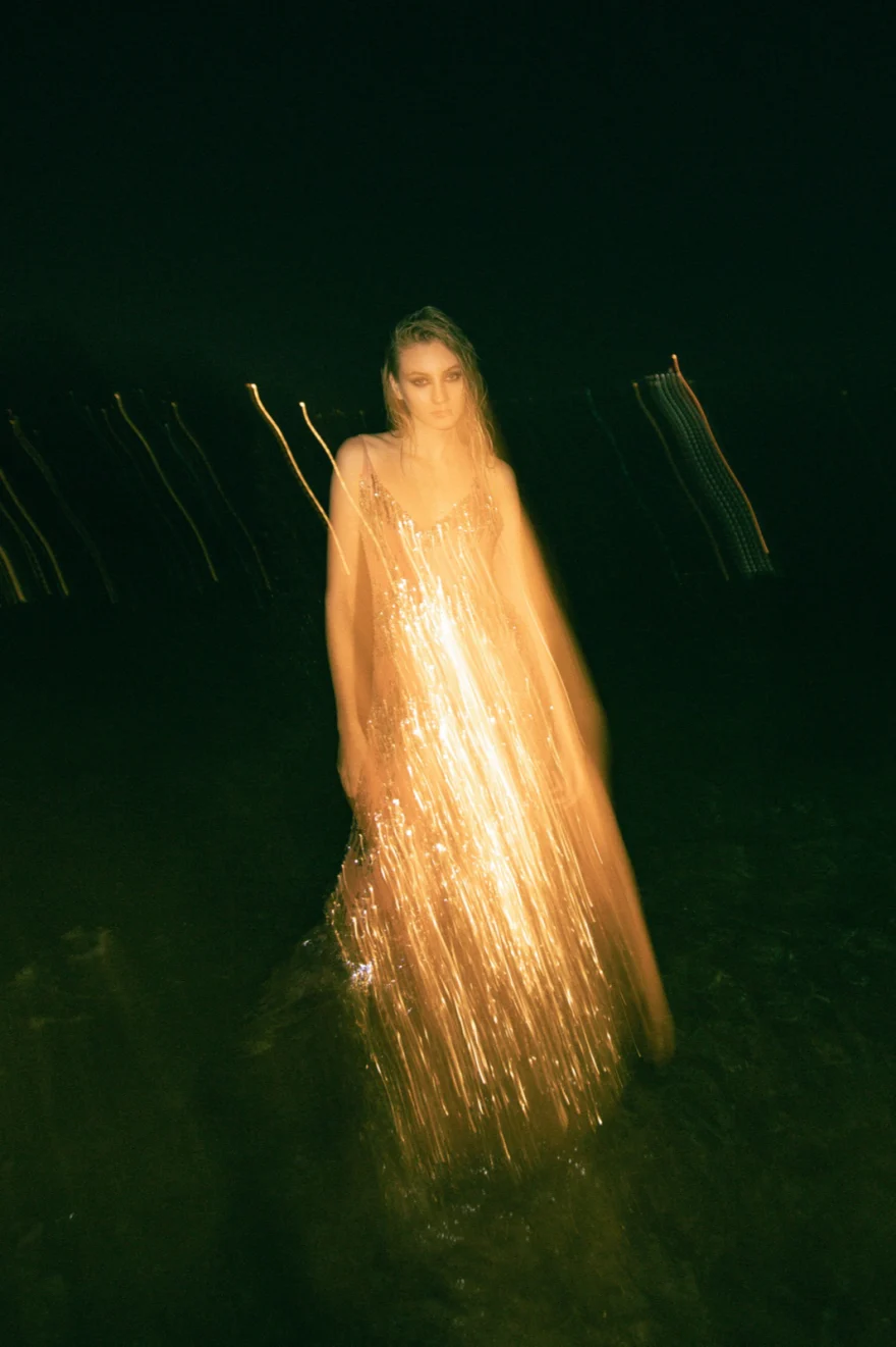 Model in a gold sequinned gown wading through water at night, Amalfi Coast personal project photographed by Ina Cenusa