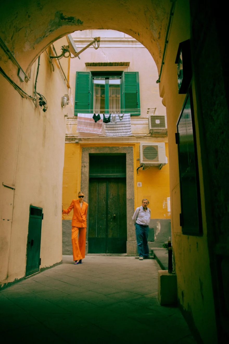 Model in orange walking through a narrow alley with green shutters, Amalfi, Amalfi Coast personal project photographed by Ina Cenusa