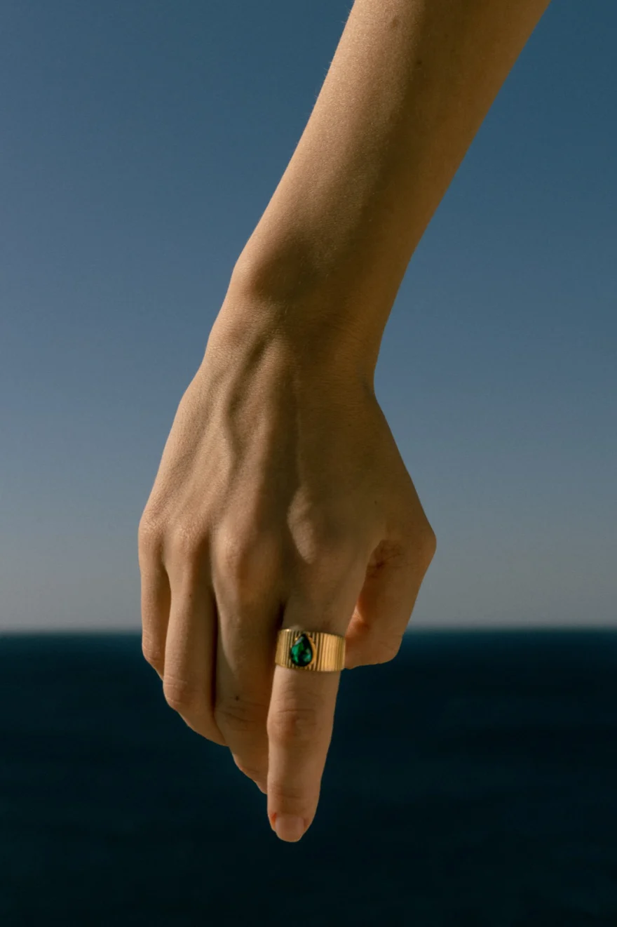 Detail of a hand wearing a green stone ring against the sea and sky, Amalfi Coast personal project photographed by Ina Cenusa