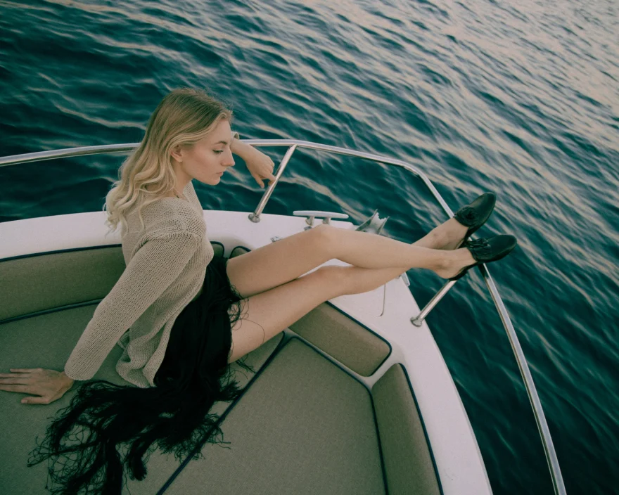 Model reclining on the bow of a boat over deep blue water, Amalfi coast editorial, Luca Grassi campaign photographed by Ina Cenusa