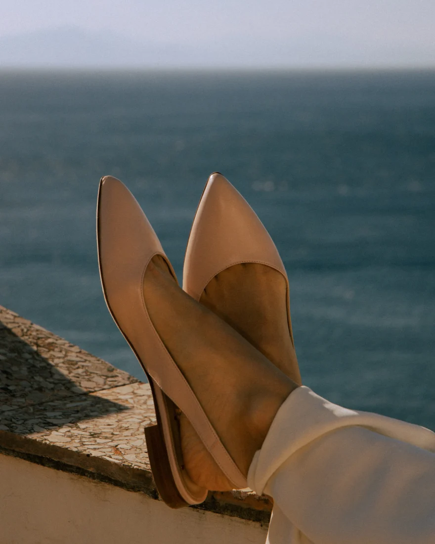 Detail shot of nude pointed flats crossed against the sea, Amalfi coast campaign, Luca Grassi campaign photographed by Ina Cenusa