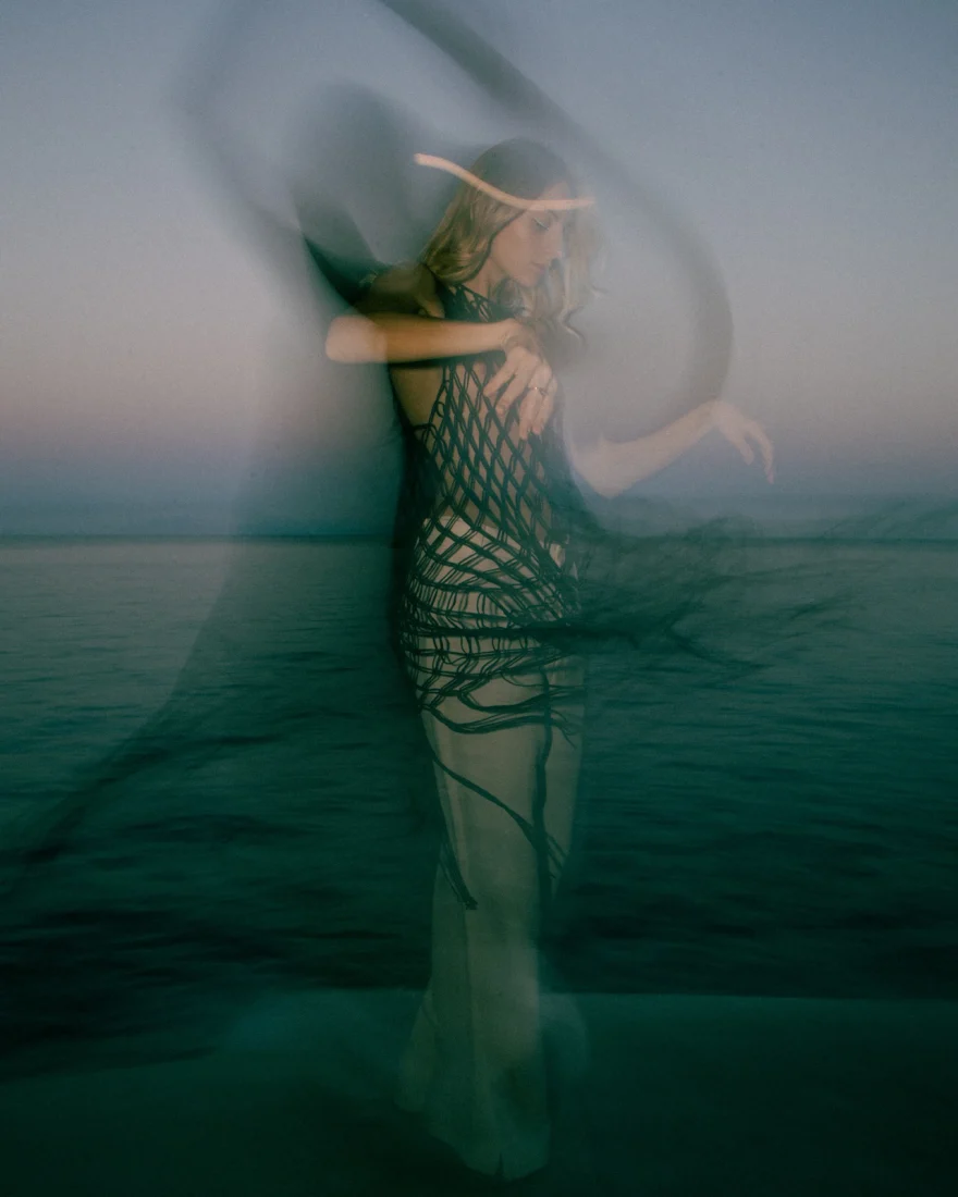 Motion-blurred fashion portrait of a model dancing by the sea at dusk, Amalfi, Luca Grassi campaign photographed by Ina Cenusa