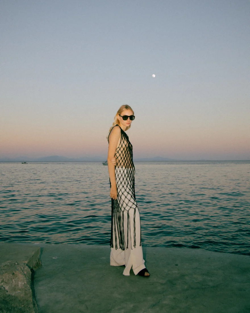Model in a net dress at the water's edge at dusk, Amalfi editorial photography, Luca Grassi campaign photographed by Ina Cenusa