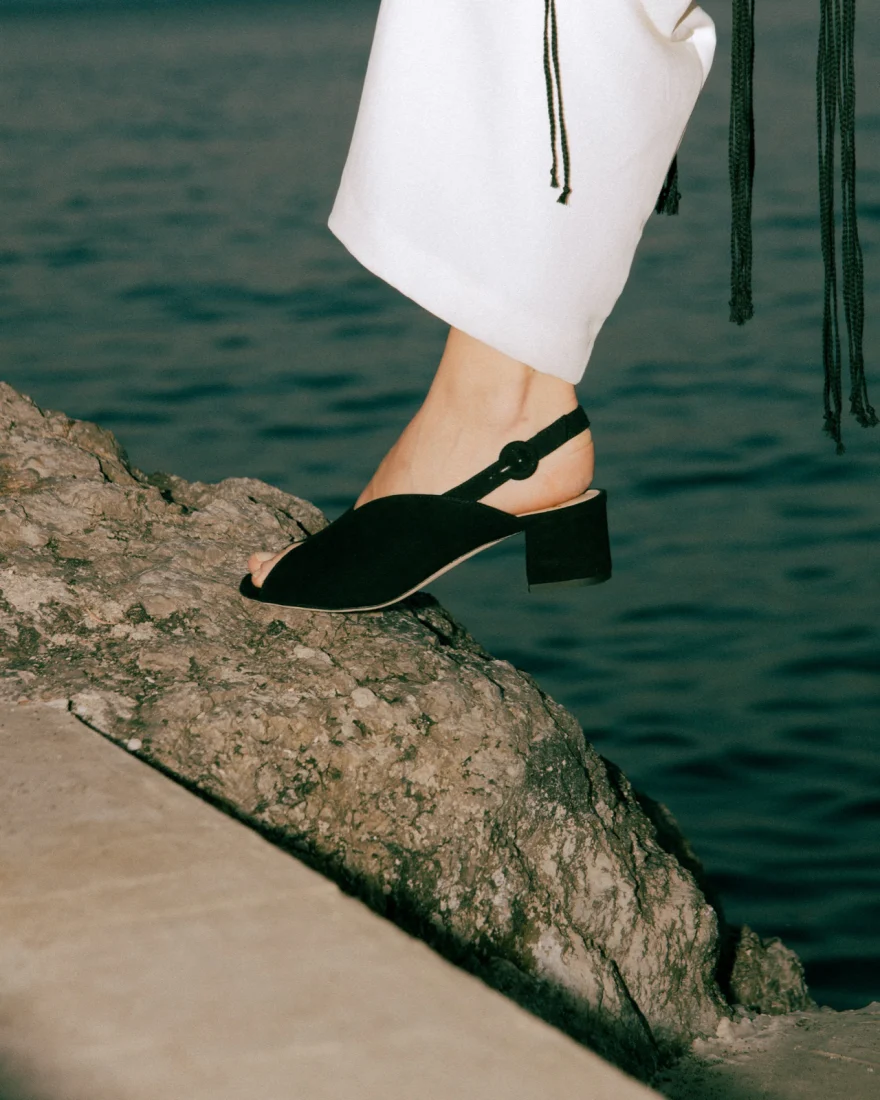 Detail of a black heeled sandal on a rock over the water, Amalfi coast, Luca Grassi campaign photographed by Ina Cenusa