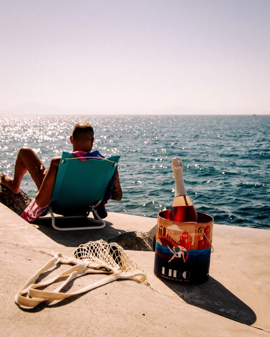 Beach chairs facing the sea with a bottle chilling in a branded bucket, Canella Wine campaign photographed by Ina Cenusa