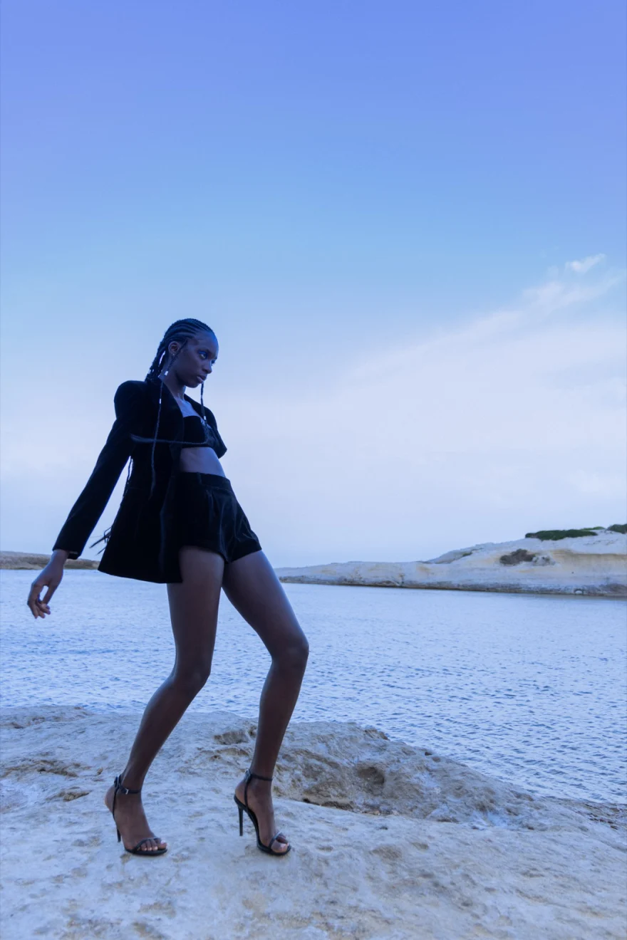 Model in a black blazer and heels walking along a pale shoreline, Ermanno Scervino × SHOT Magazine editorial photographed by Ina Cenusa