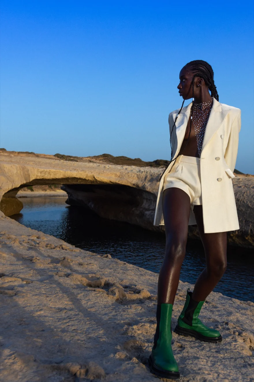 Model in a white suit and green boots by a natural rock arch on the coast, Ermanno Scervino × SHOT Magazine editorial photographed by Ina Cenusa