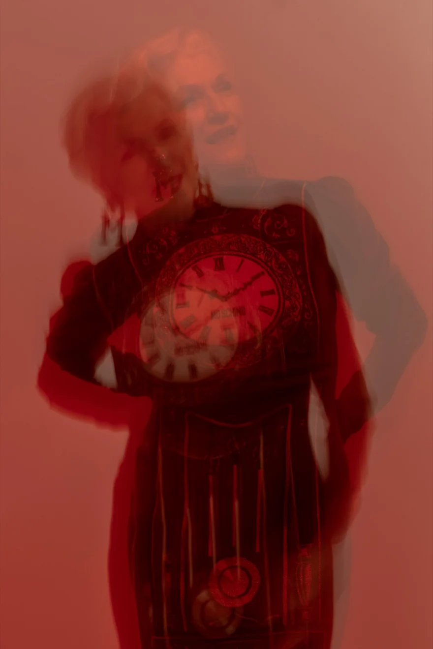Maye Musk in a red beaded fringe dress with arms raised against a deep red backdrop, SHOT Magazine campaign photographed by Ina Cenusa