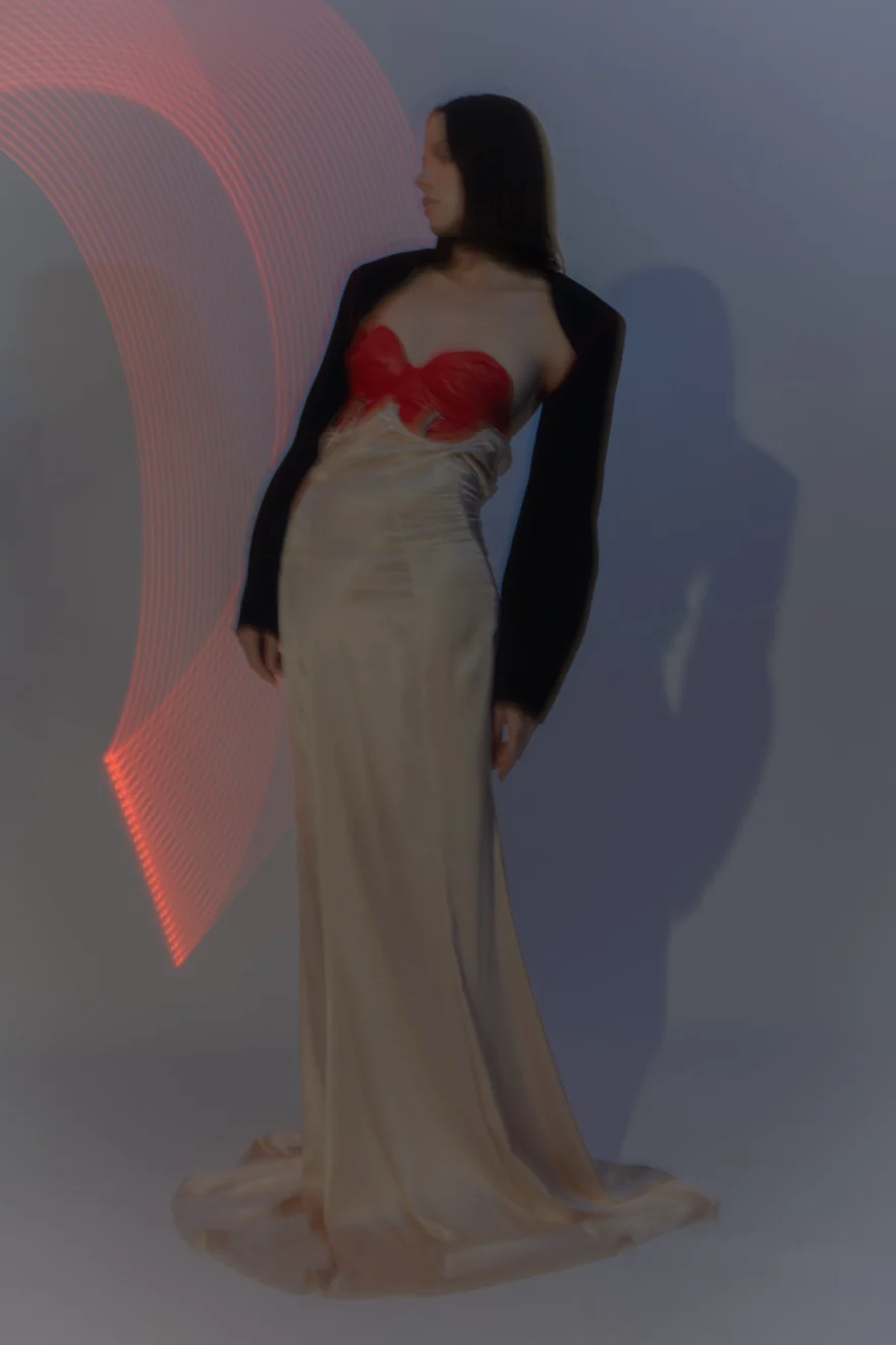 Model in a black bolero, red bustier and cream skirt against a grey studio wall, Sabina personal project photographed by Ina Cenusa