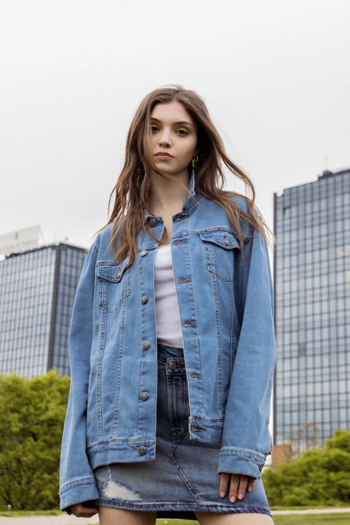 Model in an oversized denim jacket against city towers, Carrera Jeans campaign photographed by Ina Cenusa