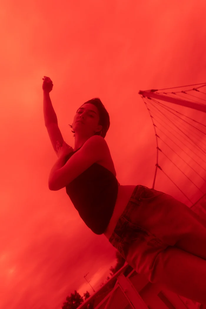 Model lit in saturated red beside a parasol, closing image of the campaign, Carrera Jeans campaign photographed by Ina Cenusa