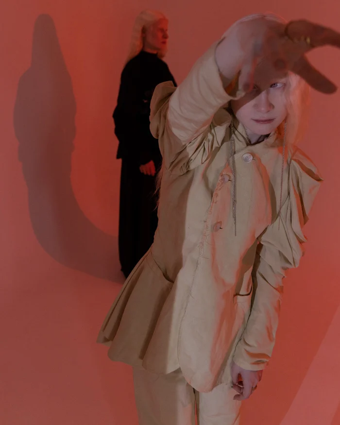 Model in a beige suit reaching towards the camera in warm orange light, SHOT Magazine editorial photographed by Ina Cenusa