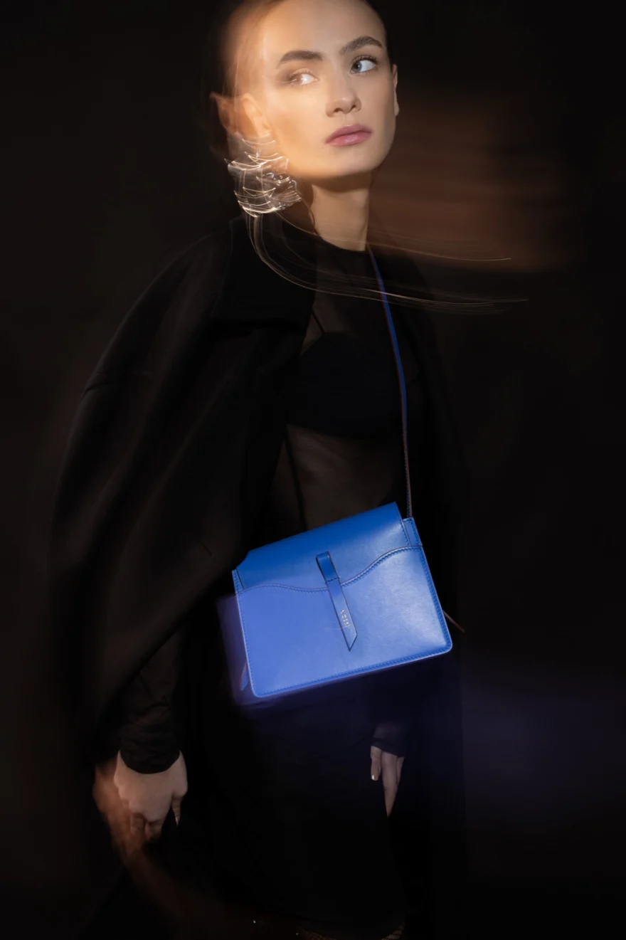 Motion-blurred portrait with a blue leather bag on black, Noesi campaign photographed by Ina Cenusa