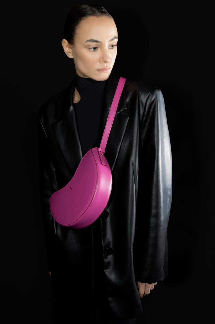 Model in black leather with a pink crescent bag, Noesi campaign photographed by Ina Cenusa