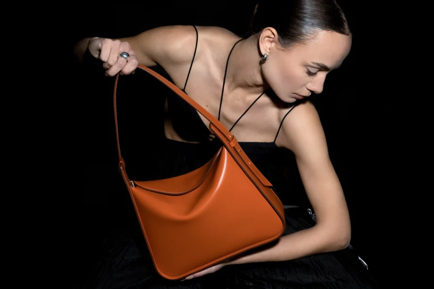 Model lifting a tan leather shoulder bag, Noesi campaign photographed by Ina Cenusa