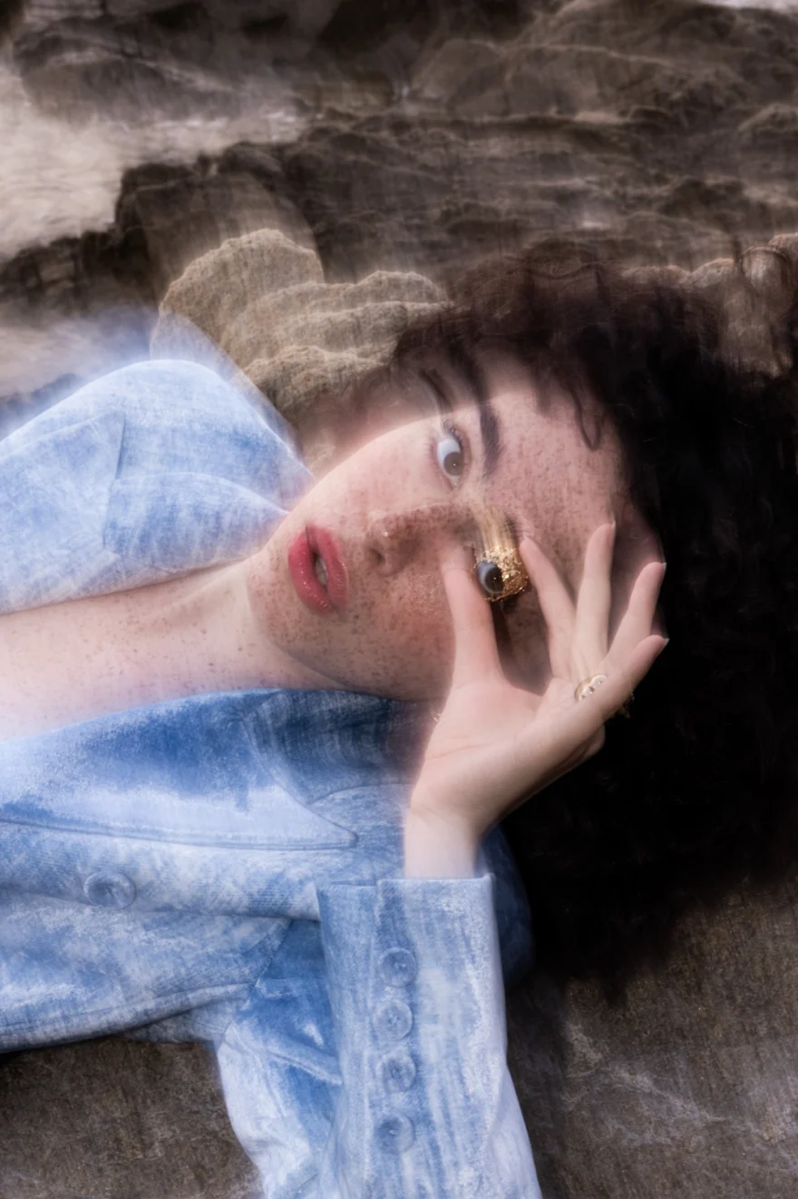 Portrait of a model in pale blue denim lying on textured rock, SHOT Magazine editorial photographed by Ina Cenusa