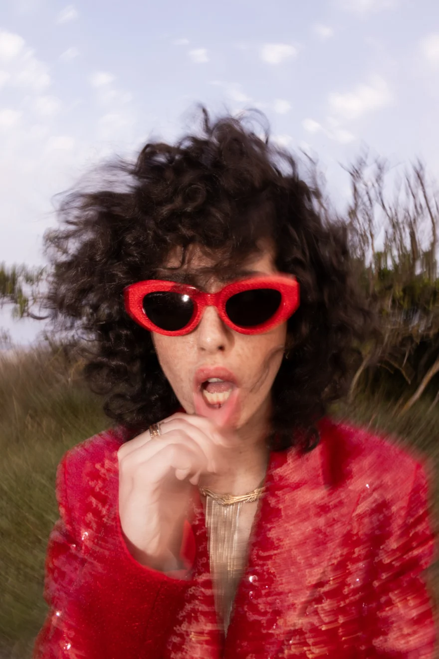 Portrait in a red sequinned jacket and red sunglasses against the sky, SHOT Magazine editorial photographed by Ina Cenusa