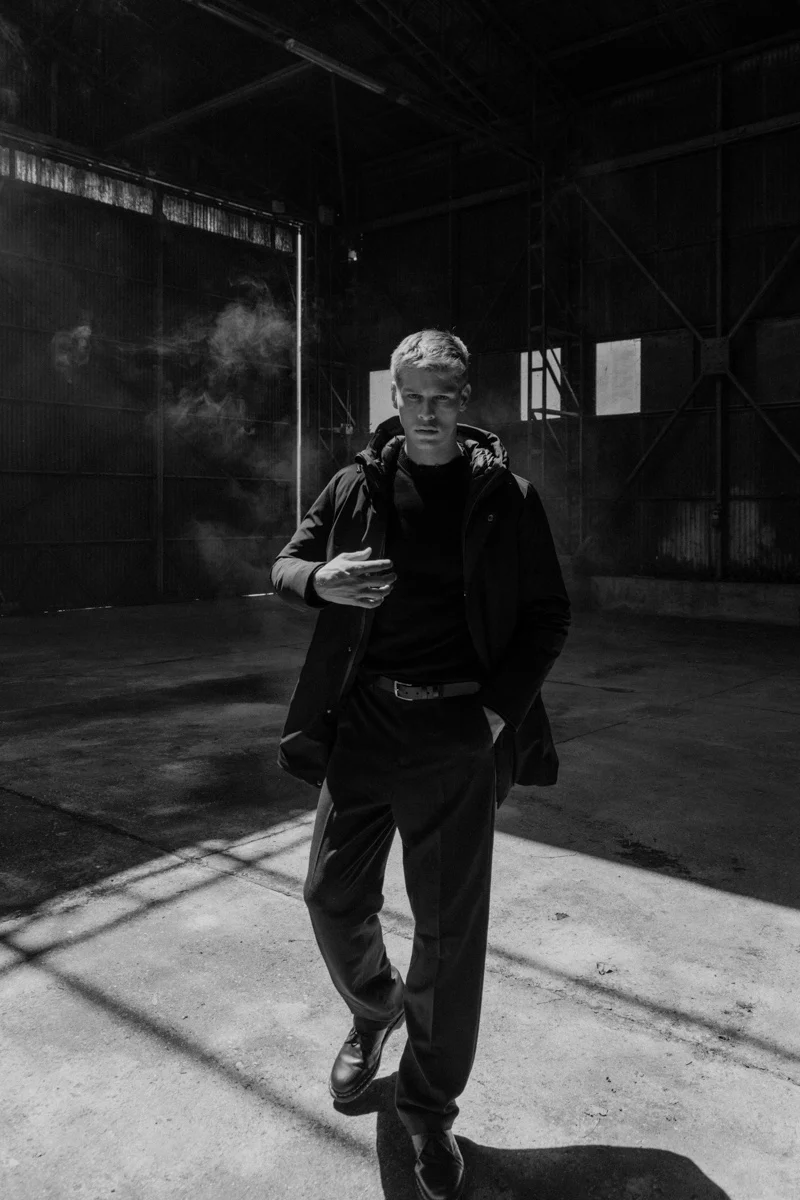 Man in dark outerwear crossing a warehouse floor, Mabrun campaign photographed by Ina Cenusa