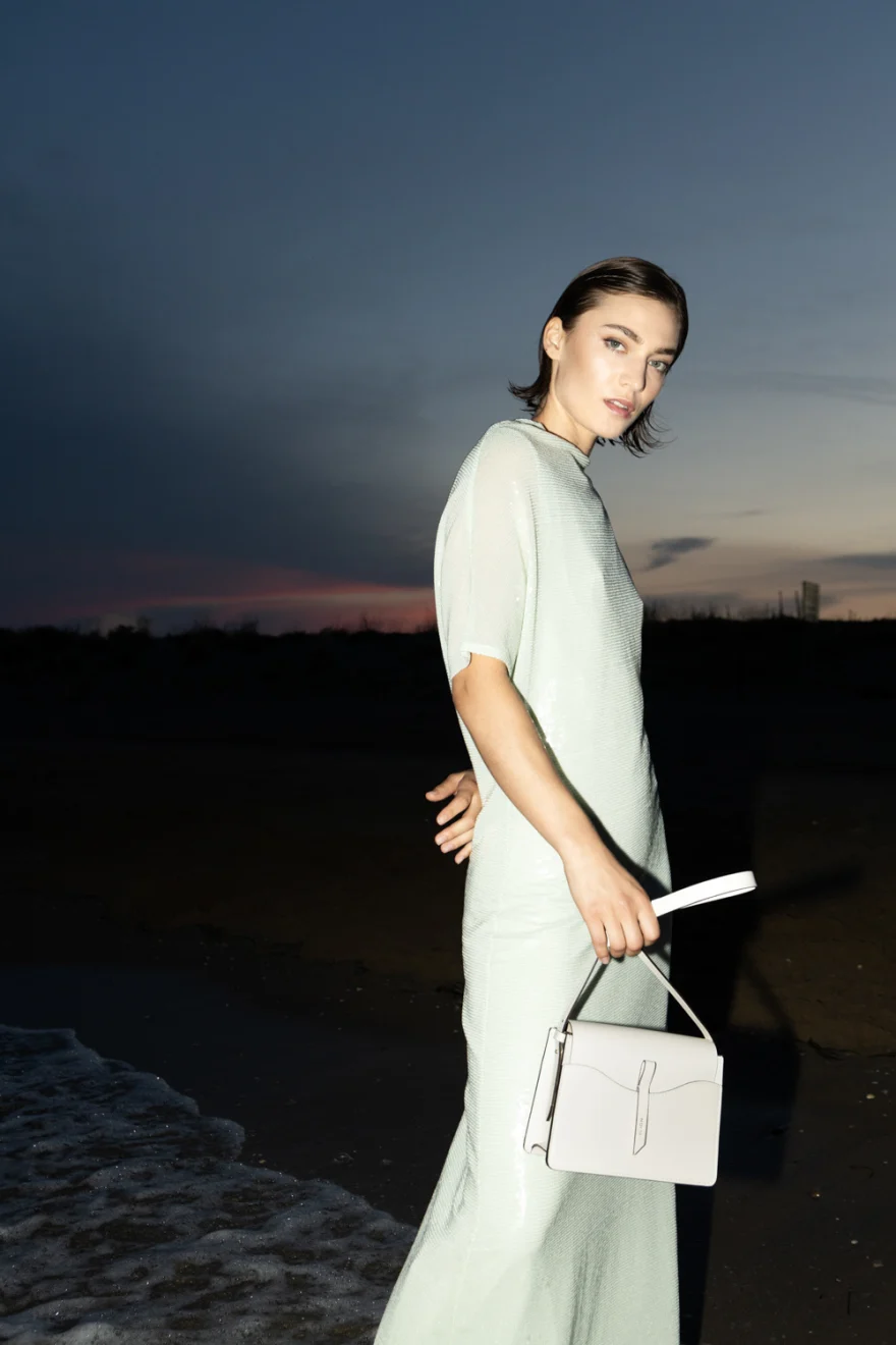 Model in a mint dress at dusk holding a white bag, Noesi campaign photographed by Ina Cenusa