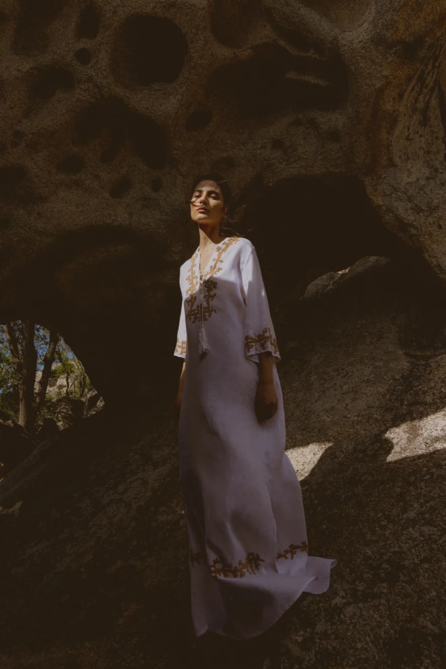 Model in a lilac embroidered kaftan framed by granite rocks, SHOT Magazine editorial photographed by Ina Cenusa