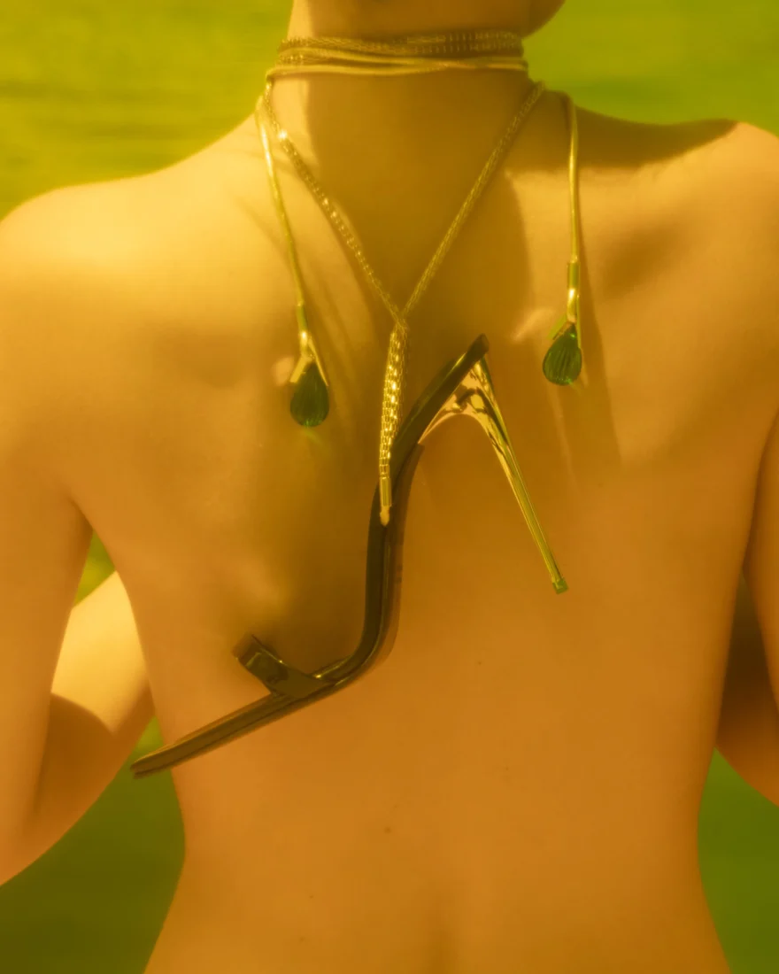 Stiletto sandal laid across a bare back with a green drop necklace, Attimu campaign photographed by Ina Cenusa