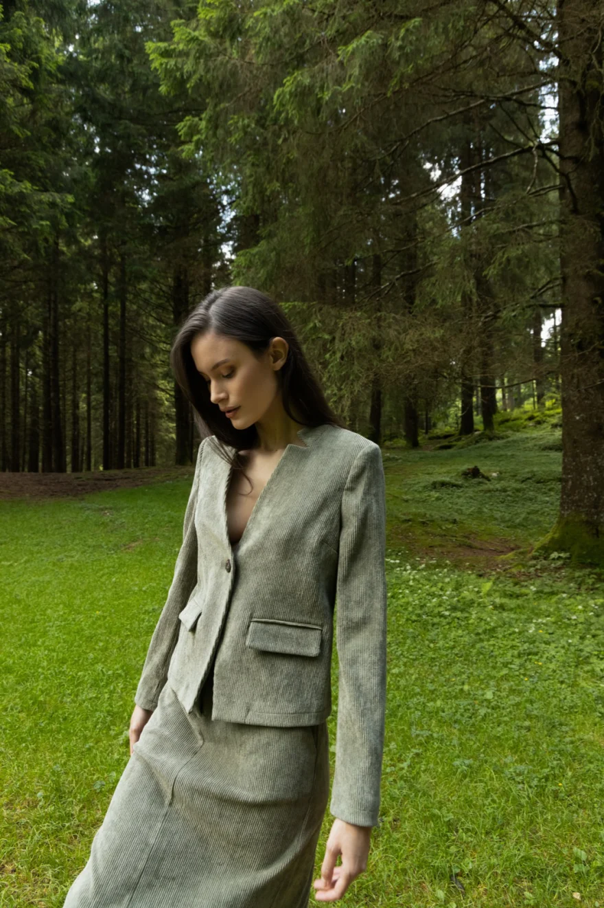 Model in a floral coat seated on mossy rocks in the woods, Camicetta Snob campaign photographed by Ina Cenusa