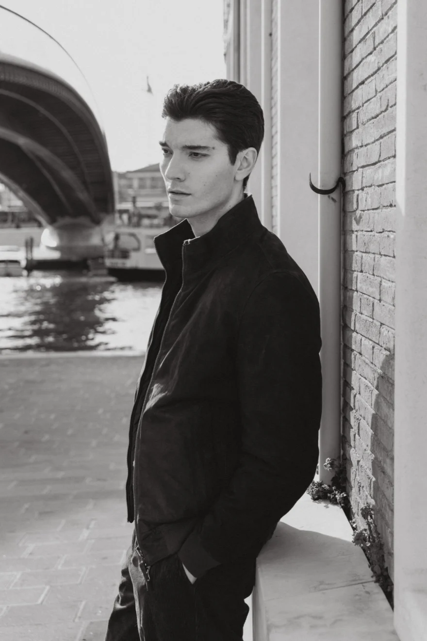 Man in a dark jacket beside a Venetian canal, Mabrun campaign photographed by Ina Cenusa