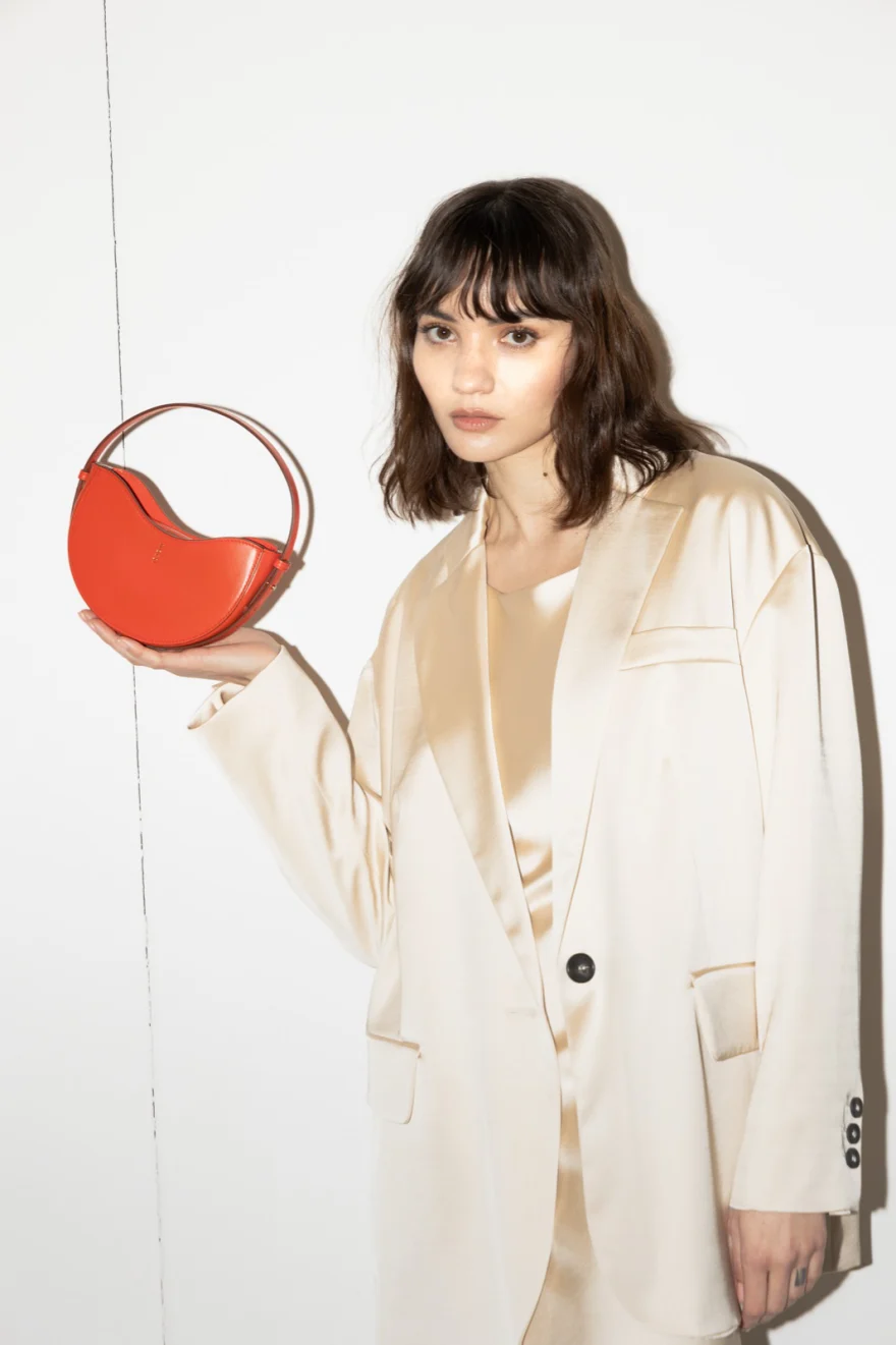 Model in a cream blazer holding a red circular bag, Noesi campaign photographed by Ina Cenusa