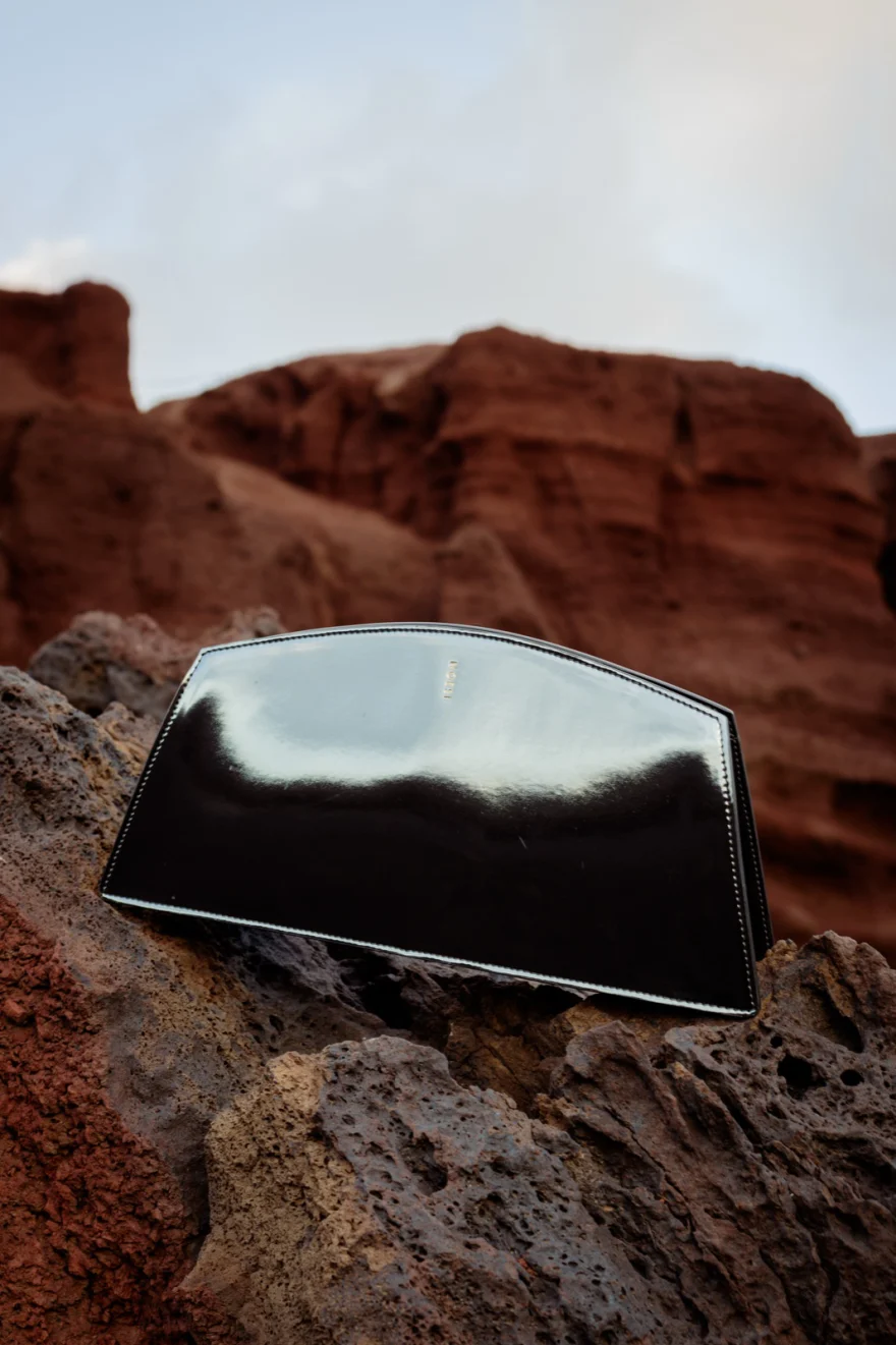 Mirror finish clutch on a rock ridge with red volcanic cliffs behind, Noesi campaign photographed by Ina Cenusa