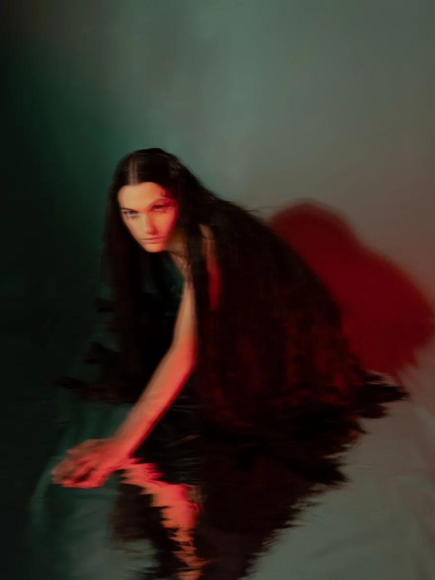 Crouching figure lit in red against green, long exposure, SHOT Magazine editorial photographed by Ina Cenusa