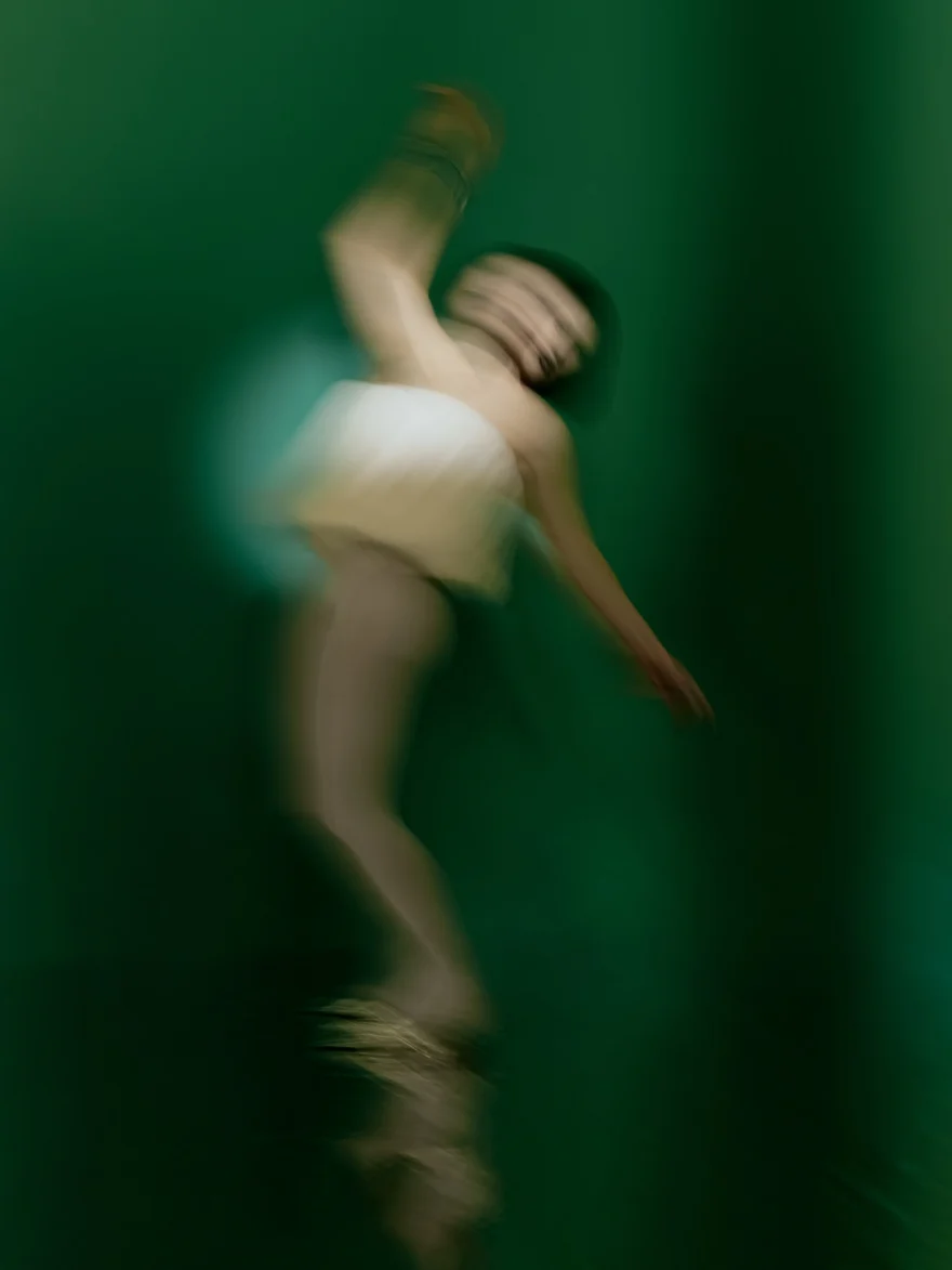 Motion-blurred figure dancing on a reflective green floor, SHOT Magazine editorial photographed by Ina Cenusa