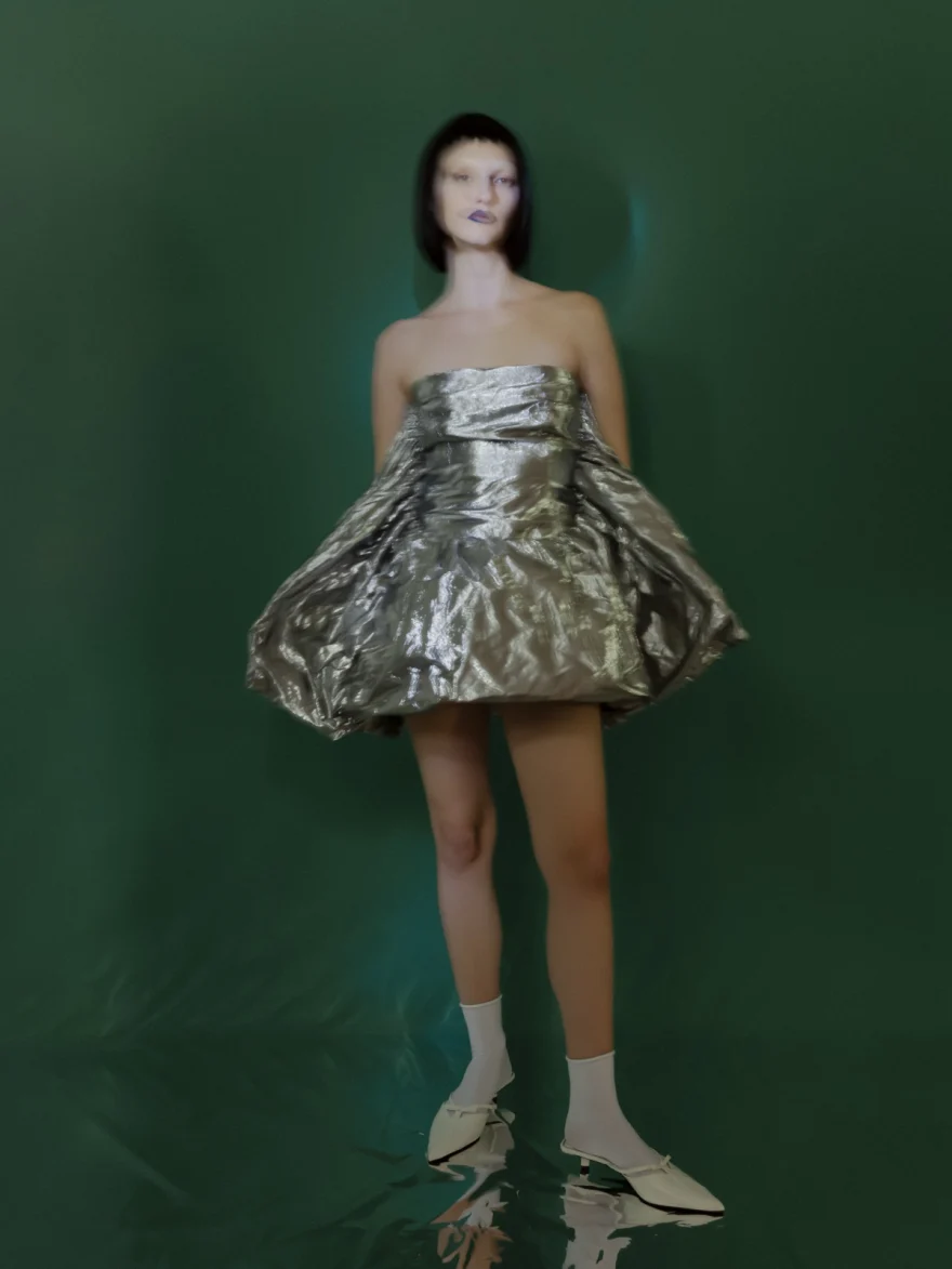 Model in a sculptural silver foil mini dress on a green set, SHOT Magazine editorial photographed by Ina Cenusa